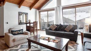 A spacious living room with a high ceiling, large windows, a sofa, a chair, and a coffee table. - Pinnacle at Deer Valley Resort - Four Bedroom Condo with Hot Tub #1263 4 Condo (Park City)