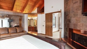 A bedroom with a large bed, a leather sofa, a stone fireplace, and a wooden ceiling. - Pinnacle at Deer Valley Resort - Four Bedroom Condo with Hot Tub #1263 4 Condo (Park City)