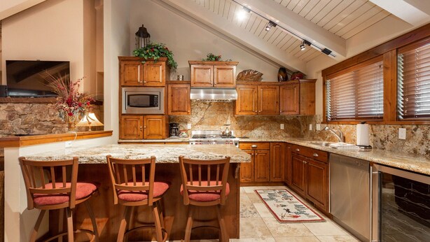A kitchen with a granite countertop, wooden cabinets, a built-in oven, and a stainless steel dishwasher.