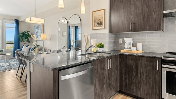 A modern kitchen with dark wood cabinets, stainless steel appliances, and a central island. - Lion s Den - 3bed - 5guest - 2 Smarttv - Hospital (Calgary)