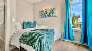A bedroom with a bed, a window with curtains, a painting on the wall, and a ceiling light fixture. - Lion s Den - 3bed - 5guest - 2 Smarttv - Hospital (Calgary)