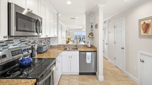 A modern kitchen with white cabinets, stainless steel appliances, and a granite countertop.