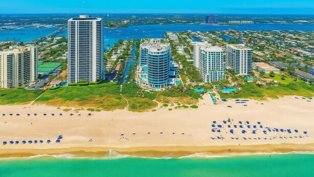 Zona hotelera costera con edificios altos, una playa de arena y un puerto deportivo.