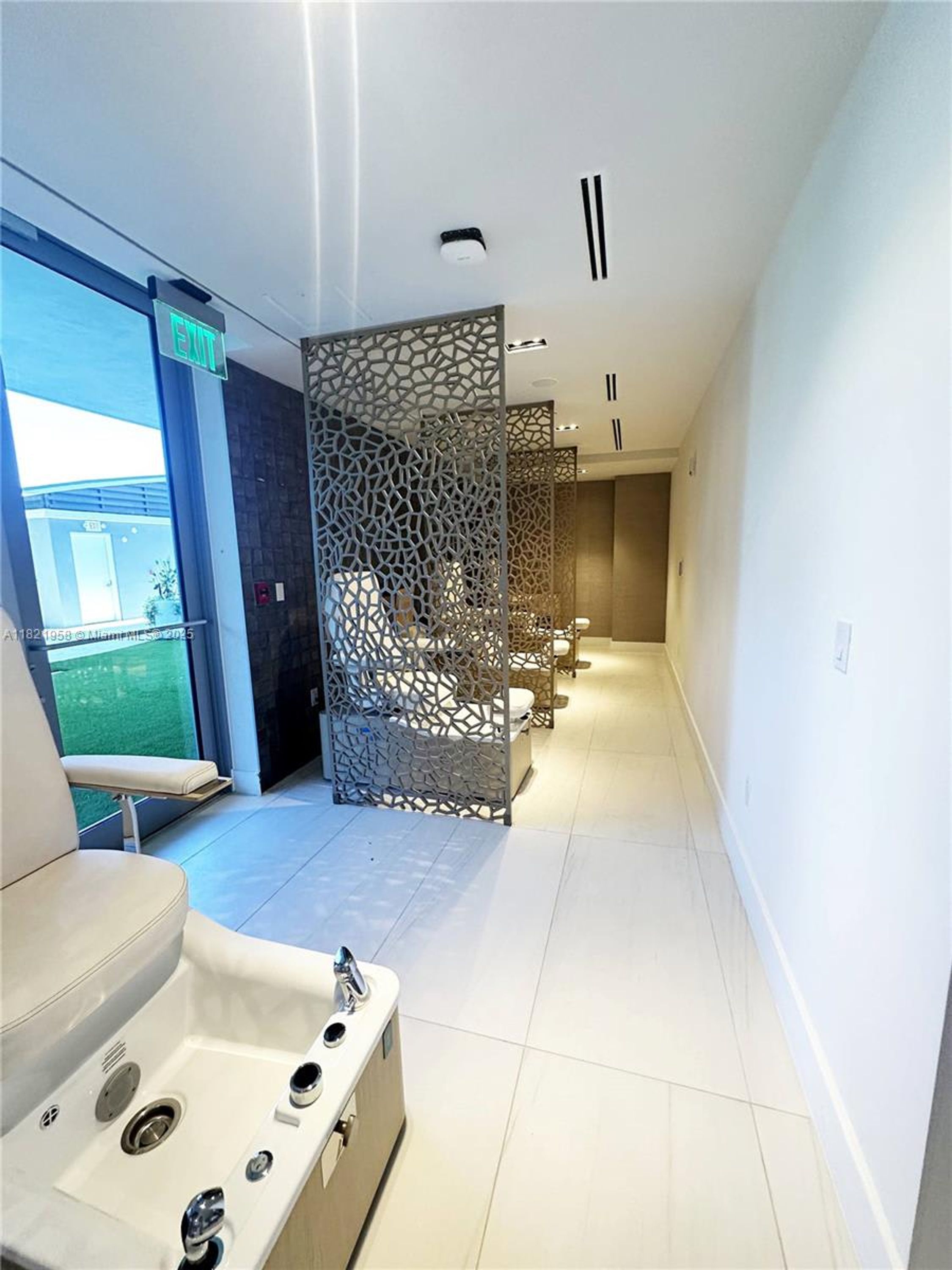 Un espace spa moderne comprenant un coin salon, un élément de séparation décoratif et un panneau de signalisation indiquant clairement la sortie.