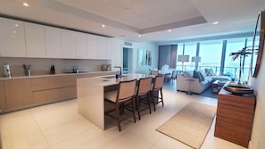 A modern kitchen with a central island, dining area with chairs, and a living room with a sofa and coffee table. - NEW Amrit Resort Oceanview Retreat (Singer Island)