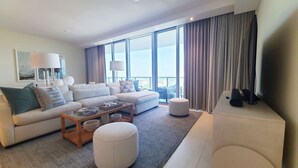 Una habitación de hotel moderna con un sofá grande, una mesa de centro y un televisor.