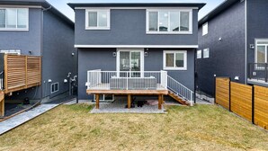 A modern two-story residential building with a wooden deck and a small backyard. - Golden Retreat - Games Movie Room - 8BD - 5bath (Calgary)
