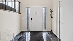 A clean, modern hallway with a double door, a coat rack, and a staircase. - Golden Retreat - Games Movie Room - 8BD - 5bath (Calgary)