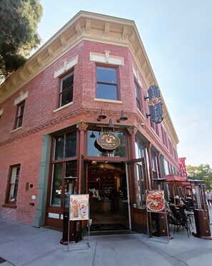 A corner building with a brick facade, large windows, and a storefront with a sign reading "Urth Cafe."