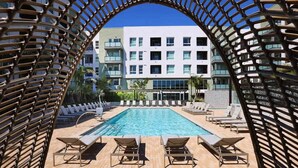 A pool area with lounge chairs and a view of a multi-story building. - Sunlit Retreat 10 Min From Disneyland With Pool GYM (Santa Ana)