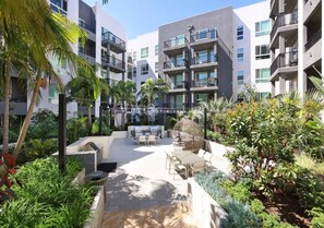 A courtyard with outdoor seating, palm trees, and a pool. - Urban Chic Home 10 Min From Disneyland With Pool GYM (Santa Ana)