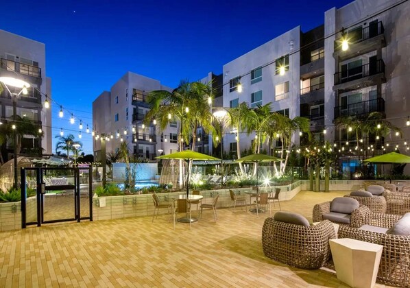 An outdoor patio area with seating, palm trees, and string lights. - Urban Chic Home 10 Min From Disneyland With Pool GYM (Santa Ana)