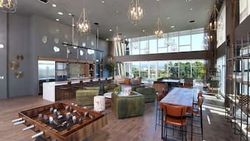 A spacious living area with a foosball table, comfortable seating, and large windows offering views of the outdoors.