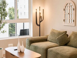 A living room with a green sofa, a wooden coffee table, and a floor lamp. - Pacific Paradise 10 Min From Disneyland With Pool GYM (Santa Ana)