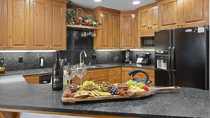A kitchen with wooden cabinets, a black refrigerator, and a countertop with a charcuterie board.