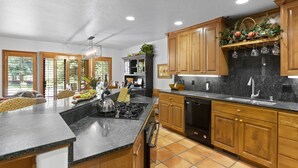 A modern kitchen with wooden cabinets, a granite countertop, and a built-in dishwasher.
