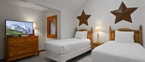 Habitación de hotel con dos camas, un aparador de madera, un televisor y decoraciones de pared con forma de estrella.