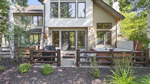 A two-story house with a patio area, outdoor seating, and a hot tub.