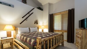 A bedroom with a wooden bed, two bedside tables with lamps, a television, and a window with curtains. - Comstock Lodge - Two Bedroom Condo with Hot Tub #306 by Deer Valley Resort (Park City)