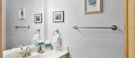 A bathroom with a sink, mirror, towel rack, and framed pictures on the wall.