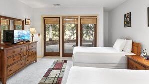 A hotel room with a large sliding glass door to the outdoors, a wooden dresser with a flat-screen TV, two single beds, and a bedside table with a phone. - Aspenwood at Deer Valley Resort - Three Bedroom Condo with Hot Tub #1305 3 Condo (Park City)