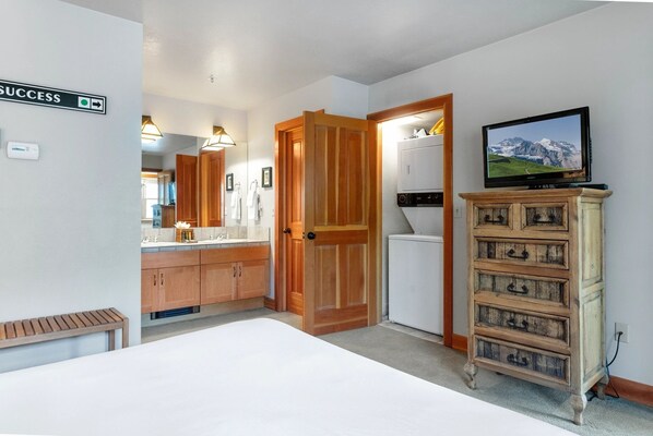 Una habitación de hotel con una puerta de madera, un televisor en un mueble y un letrero que indica una dirección.