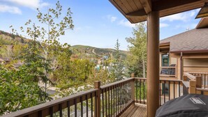 Une terrasse en bois offrant une vue sur un quartier résidentiel et sur des collines en arrière-plan.