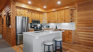 Une cuisine moderne avec des meubles en bois, des appareils en acier inoxydable et un îlot central doté de tabourets.
