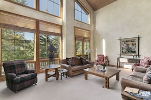A spacious living room with large windows, a fireplace, and a cozy seating area. - Thistle Drive Home at Deer Valley Resort - 4 Bedroom Home #3020 4 Condo (Park City)