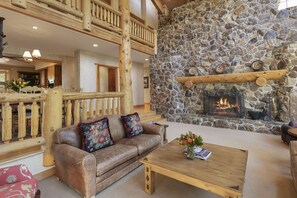 A cozy living room with a stone fireplace, wooden furniture, and a high wooden ceiling. - Thistle Drive Home at Deer Valley Resort - 4 Bedroom Home #3020 4 Condo (Park City)