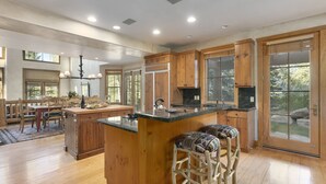 A spacious kitchen with wooden cabinets, a large island, and a dining area with a table and chairs.