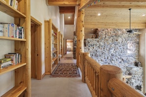 A wooden hallway with bookshelves, a stone wall, and a carpeted floor. - Thistle Drive Home at Deer Valley Resort - 4 Bedroom Home #3020 4 Condo (Park City)