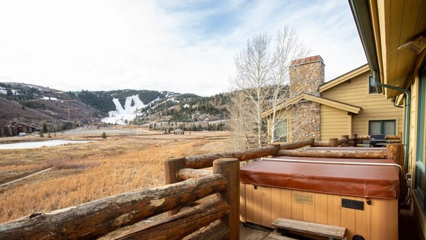 A wooden deck with a hot tub and a wooden bench, overlooking a snowy mountain and a valley. - Bristlecone at Deer Valley Resort - Three Bedroom Condo with Loft and Hot Tub #504 3 Condo (Park City)