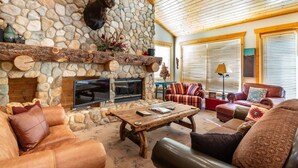 A cozy living room with a stone fireplace, leather sofas, and a television. - Bristlecone at Deer Valley Resort - Three Bedroom Condo with Loft and Hot Tub #504 3 Condo (Park City)