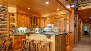 A wooden cabin-style kitchen with a central island, bar stools, and built-in appliances. - Bristlecone at Deer Valley Resort - Three Bedroom Condo with Loft and Hot Tub #504 3 Condo (Park City)