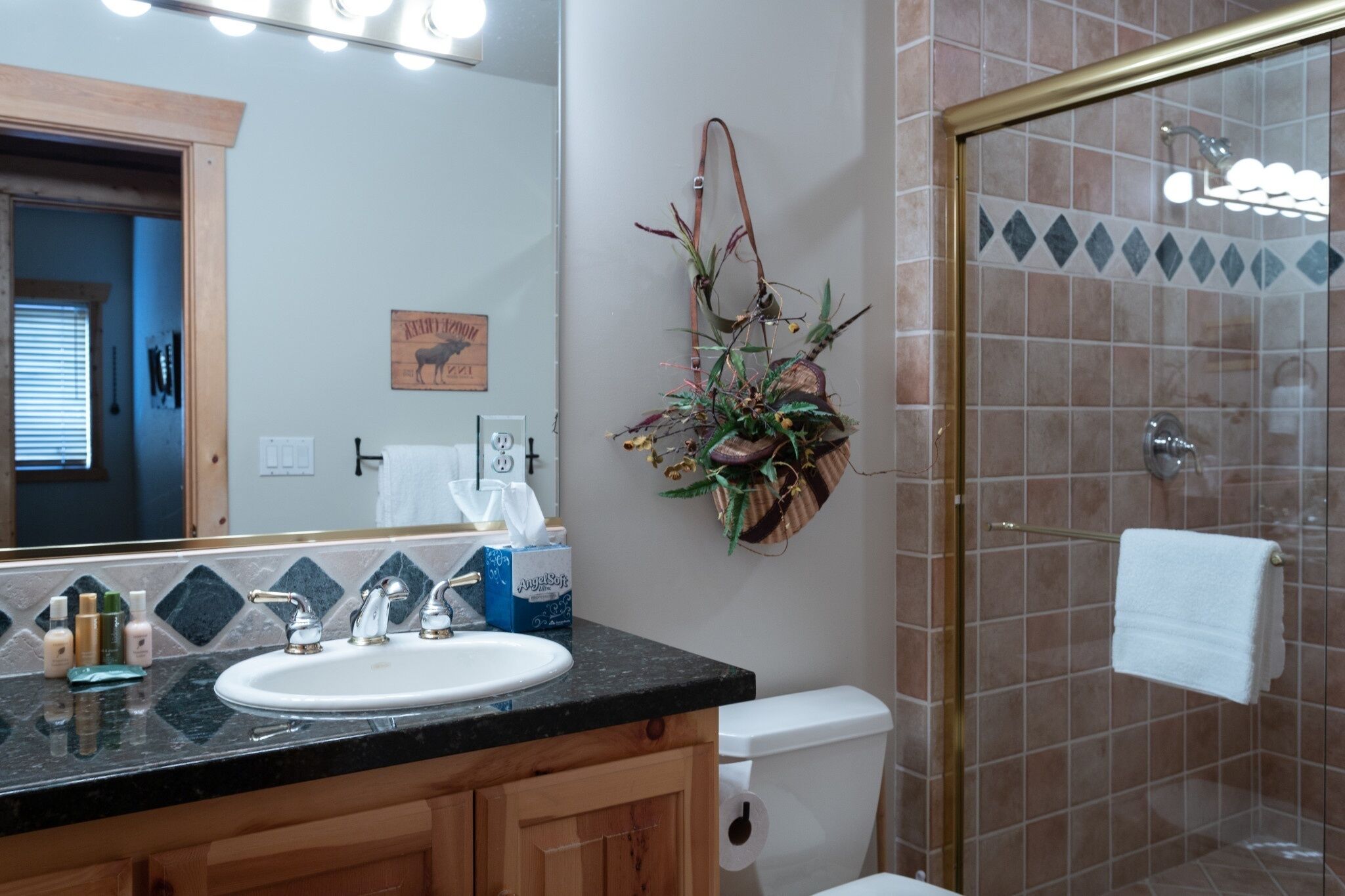 A bathroom with a sink, mirror, toilet, and shower.