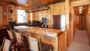 A log cabin kitchen with a central island, wooden cabinets, and a hanging light fixture. - Comstock Lodge at Deer Valley Resort - Two Bedroom Condo with Hot Tub #101 2 Condo (Park City)