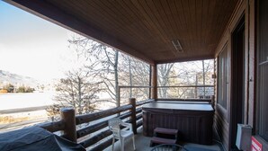 A covered outdoor area with a hot tub, chairs, and a view of a snowy landscape. - Comstock Lodge at Deer Valley Resort - Two Bedroom Condo with Hot Tub #101 2 Condo (Park City)