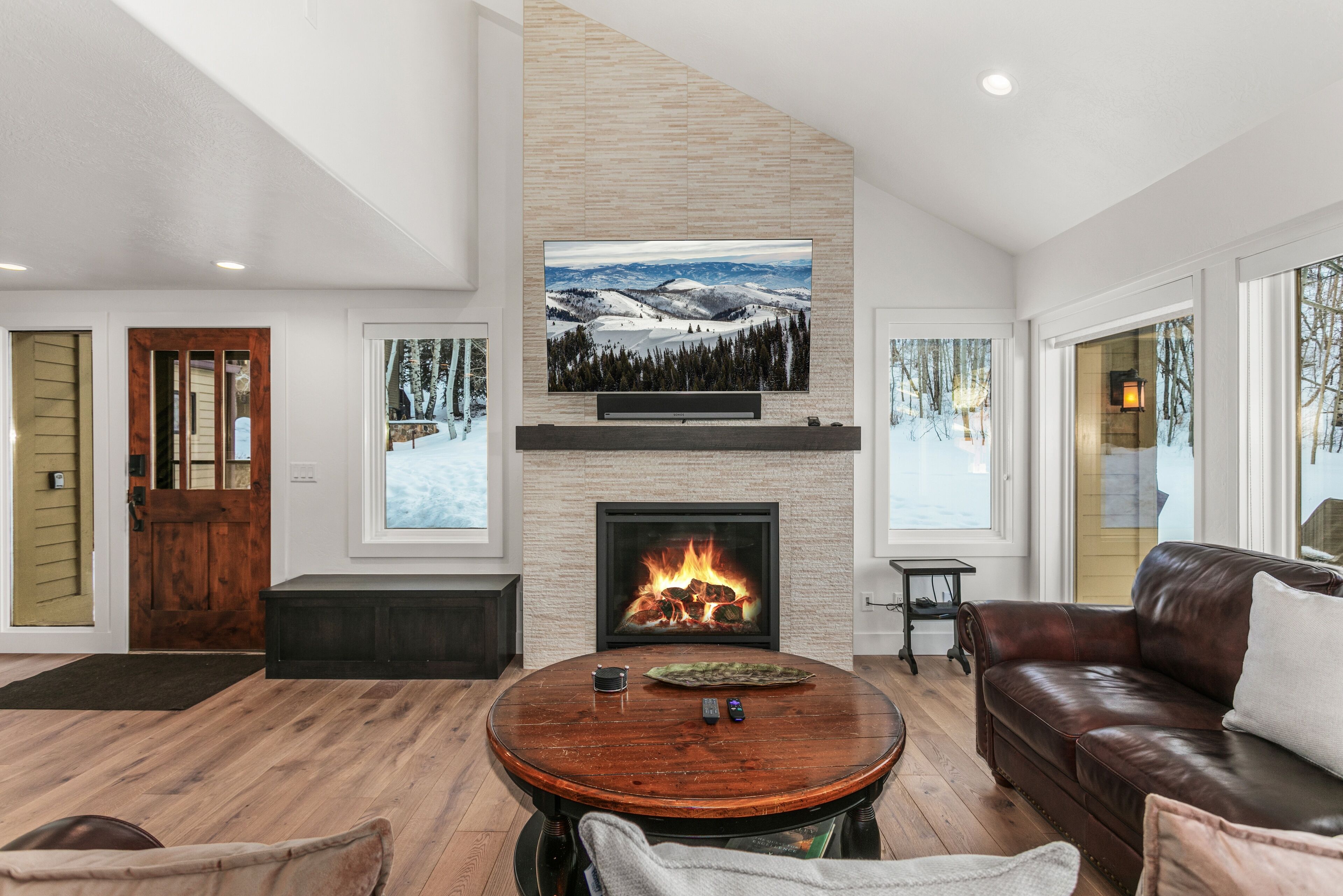 A modern living room with a fireplace, a television mounted on the wall, and a cozy seating area.