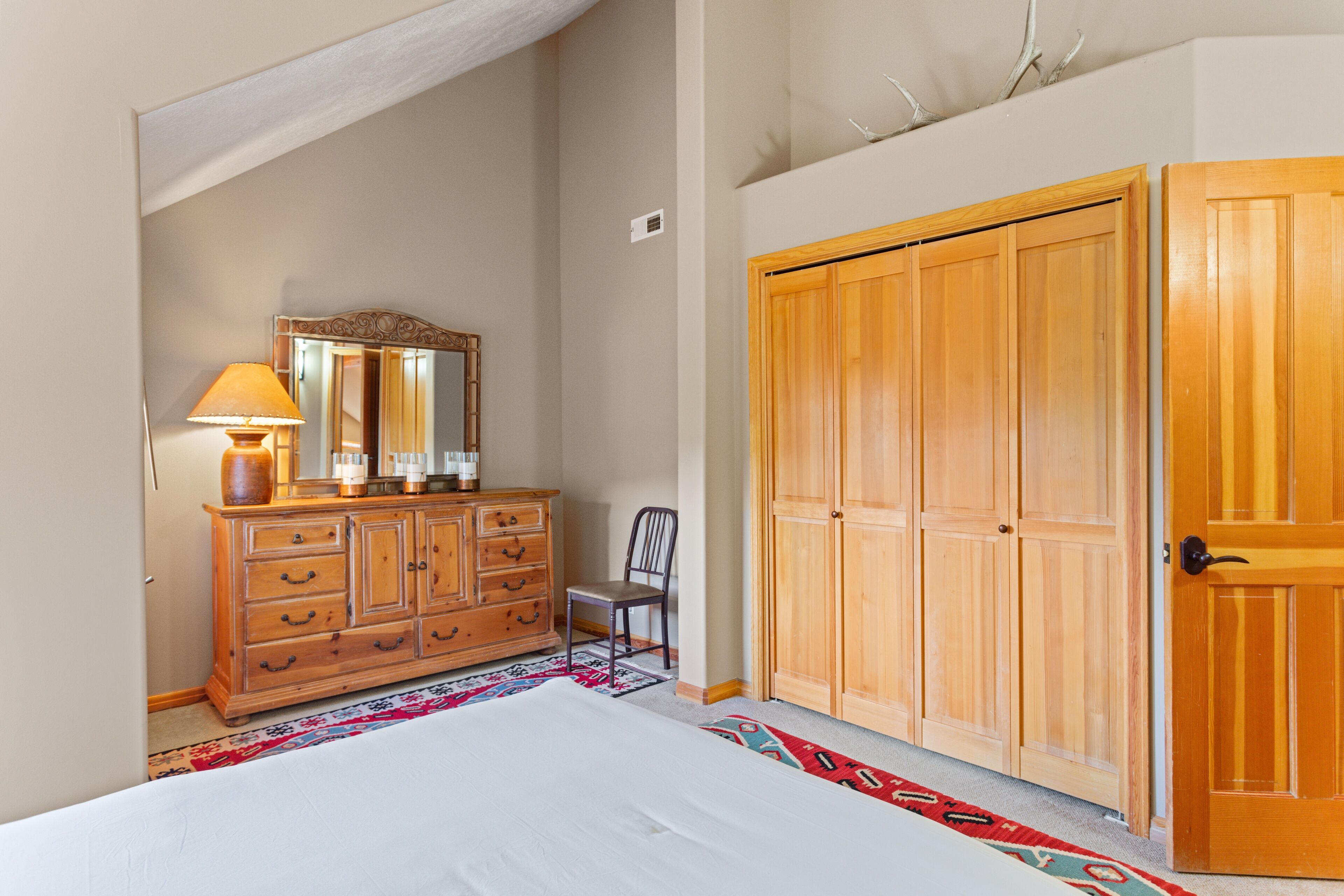 Une chambre à coucher comprenant un lit, une commode, un miroir et une armoire en bois.