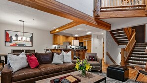 A spacious living room with a brown leather sofa, a coffee table, and a staircase leading to an upper level. - Sterling Lodge at Deer Valley Resort - Three Bedroom Condo with Hot Tub #111 3 Condo (Park City)