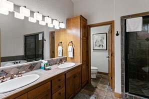 A bathroom with two sinks, a large mirror, and a shower area.