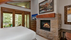 A bedroom with a stone fireplace, a bed, a wooden dresser, and a painting of a landscape. - Sterling Lodge at Deer Valley Resort - Three Bedroom Condo with Hot Tub #111 3 Condo (Park City)