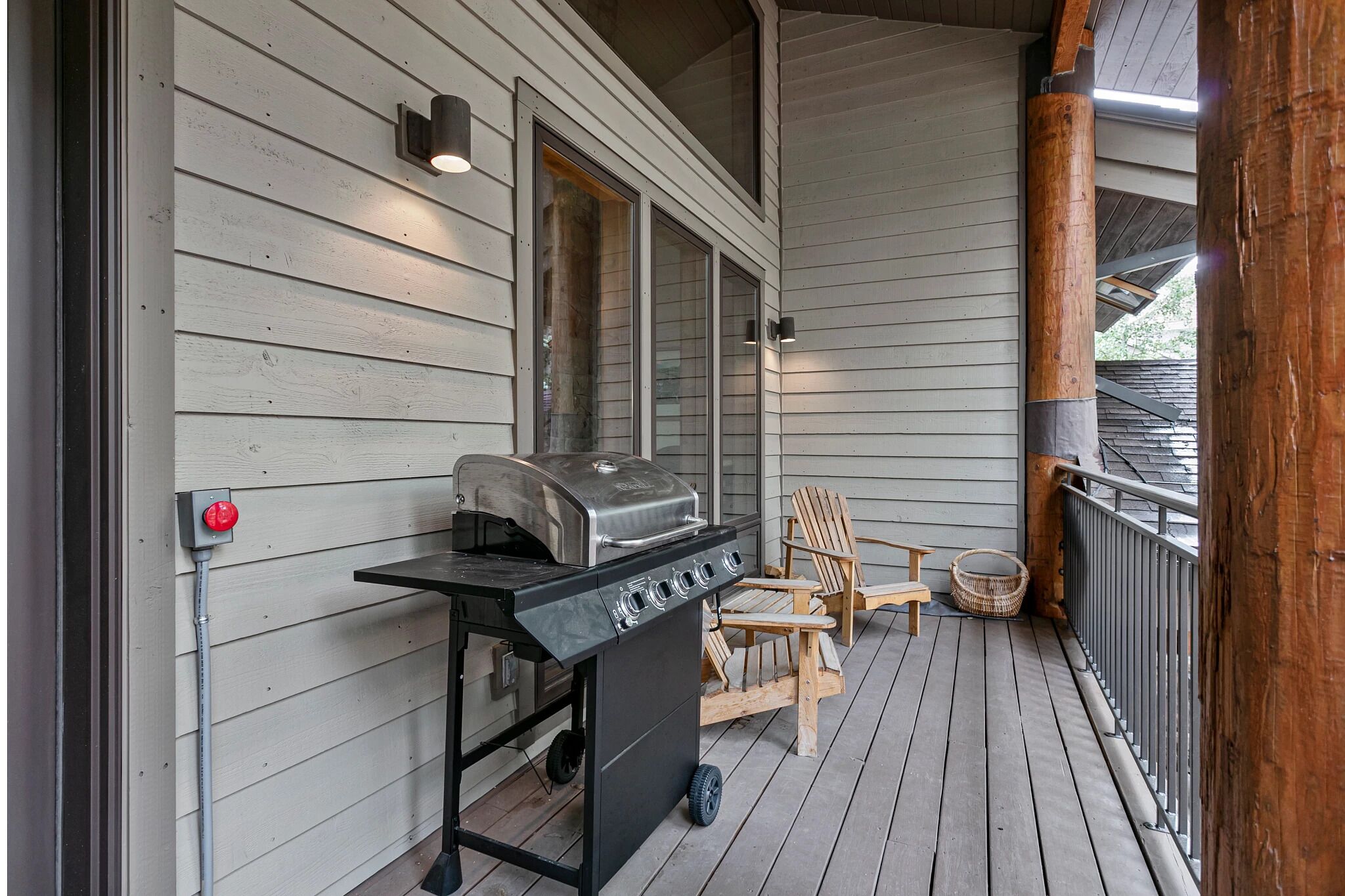A covered porch with a grill, two chairs, and a window.