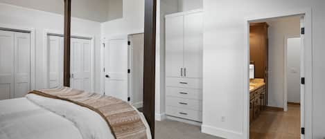 A bedroom with a four-poster bed, a walk-in closet, and a hallway leading to a bathroom.
