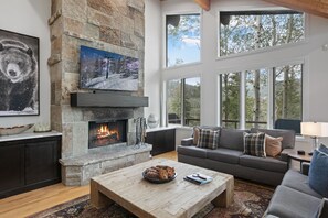 A spacious living room with a stone fireplace, a large window, and a cozy seating area. - Twin Pines at Deer Valley Resort - Three Bedroom Condo with Hot Tub #5 3 Condo (Park City)