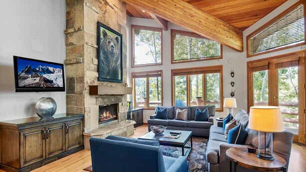 A spacious living room with a stone fireplace, large windows, and a cozy seating area.