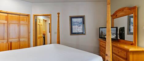 A bedroom with a large bed, wooden wardrobe, and a dresser with a mirror.