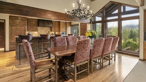 Une cuisine spacieuse avec des meubles en bois, une grande table à manger entourée de chaises à motifs et un lustre.