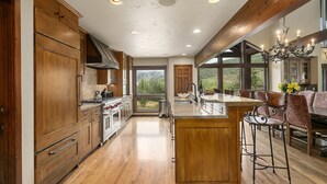 Une cuisine spacieuse avec des meubles en bois, un grand îlot central et une vue sur les montagnes par les fenêtres.